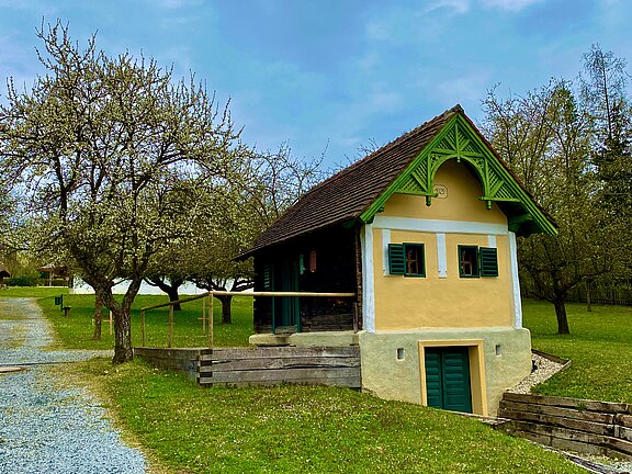 Historisches Kellerstöckl im Freilichtmuseum Bad Tatzmannsdorf, umgeben von blühenden Obstbäumen.