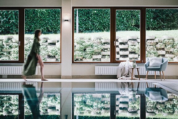 Moderner Indoor-Pool mit Liegen und großen Fensterfronten im Hotel Simon.
