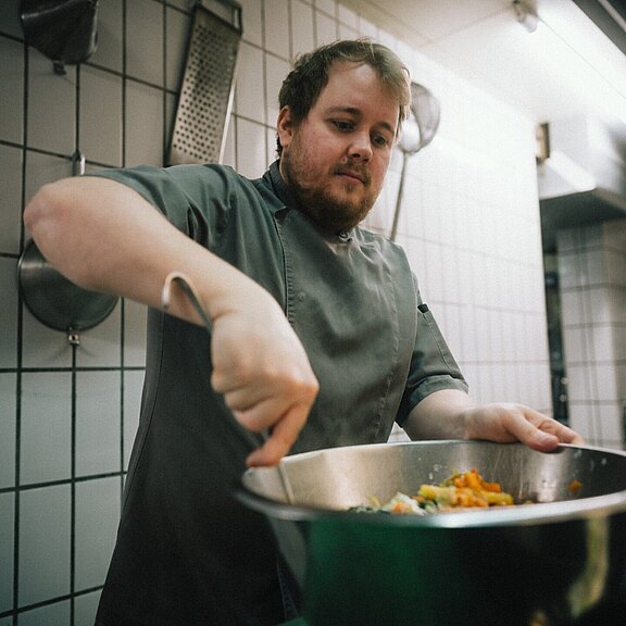 Küchenchef rührt mit Konzentration frische Zutaten in einer Metallschüssel