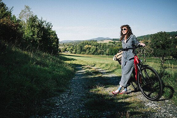 Radfahrer auf einer Landstraße durch Felder bei Sonnenuntergang im Südburgenland