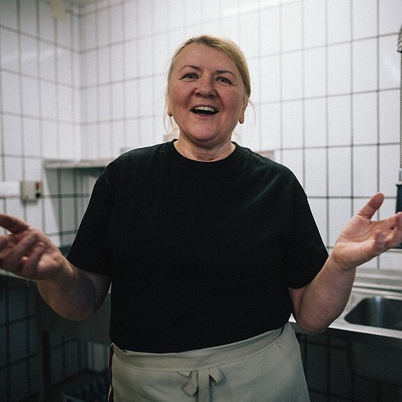 Lachende Köchin in der Hotelküche mit Kachelhintergrund